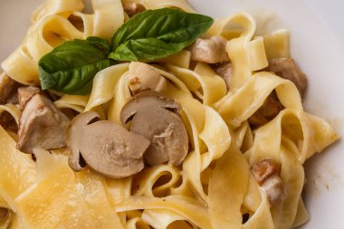 Fesleğen ile süslenmiş Mantarlı Tagliatelle vejetaryen Makarna Yemeği. Makarna ve beyaz mantar ile lezzetli öğle yemeği. Ahşap arka planda.