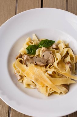 Fesleğen ile süslenmiş Mantarlı Tagliatelle vejetaryen Makarna Yemeği. Makarna ve beyaz mantar ile lezzetli öğle yemeği. Ahşap arka planda.