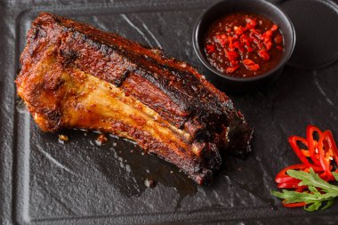 Izgara ve barbekü sıcak domuz kaburga sıcak biber ve siyah taş arka plan üzerinde sıcak sos ile. Izole. Erkekler için yemek. Baharatlı