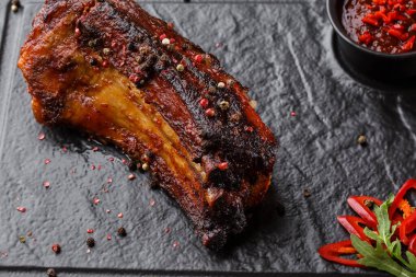 Izgara ve barbekü sıcak domuz kaburga sıcak biber ve siyah taş arka plan üzerinde sıcak sos ile. Izole. Erkekler için yemek. Baharatlı