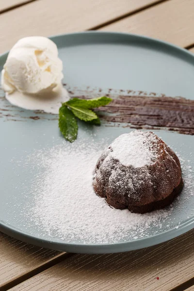 Köstliche frische Fondant mit heißer Schokolade und Eis und Minze auf Teller serviert. Lavakuchenrezept. Hölzerner Hintergrund. — Stockfoto