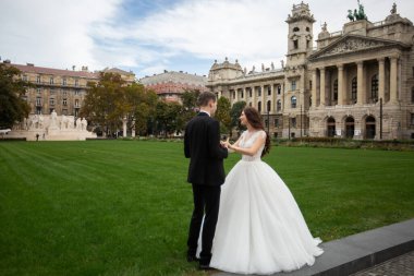 Gelin ve damat eski kasaba caddesinde sarılıyor. Düğün çifti Budapeşte 'de Parlamento Binası yakınlarında yürüyor. Kafkasyalı mutlu romantik çift evliliklerini kutluyor. Düğün ve aşk konsepti.