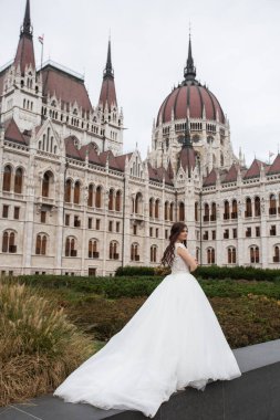 Eski şehir sokağındaki gelin. Düğün Budapeşte 'de Parlamento Binası yakınlarında. Kafkasyalı mutlu romantik kadın evliliğini kutluyor. Düğün ve aşk konsepti.