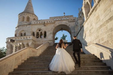 Gelin ve damat eski kasaba caddesinde sarılıyor. Budapeşte, Macaristan 'da Balıkçı Kalesi' nde yürüyen düğün çifti. Evliliklerini kutlayan mutlu romantik genç çift. Düğün ve aşk konsepti.