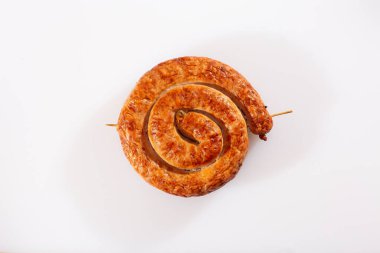 Beyaz arka planda geleneksel spiral şeklinde salyangoz sosisi. Izgara yuvarlak sosis. Lezzetli barbekü. Doğal kabuklu lezzetli bir geleneksel köy sosisi var, salyangoza sarılmış..