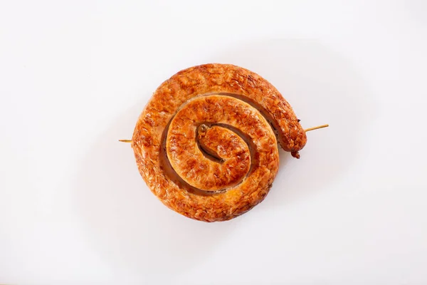 Beyaz arka planda geleneksel spiral şeklinde salyangoz sosisi. Izgara yuvarlak sosis. Lezzetli barbekü. Doğal kabuklu lezzetli bir geleneksel köy sosisi var, salyangoza sarılmış..