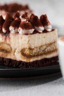 Tiramisu, mascarpone ve kahveli klasik tatlı. Hafif mermer arka planda koyu bir tabakta nefis bir Tiramisu keki. Dikey fotoğraf.