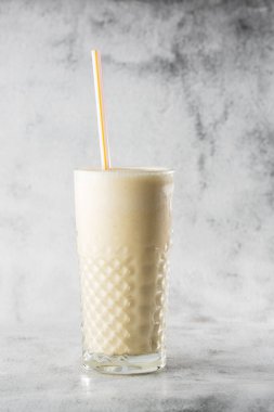 Muzlu yulaf püresi ya da parlak mermer arka planda bardakta vanilyalı milkshake. Genel görünüm, kopyalama alanı. Milkshake kafe menüsü reklamı. Dikey fotoğraf.