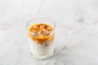 Parlak mermer zemin üzerinde soğuk kahve ve süt ile izole edilmiş bir bardak. Genel görünüm, kopyalama alanı. Kafe menüsü reklamı. Kahve dükkanı menüsü. Yatay fotoğraf.