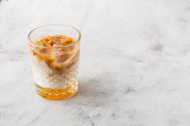 Parlak mermer zemin üzerinde soğuk kahve ve süt ile izole edilmiş bir bardak. Genel görünüm, kopyalama alanı. Kafe menüsü reklamı. Kahve dükkanı menüsü. Yatay fotoğraf.