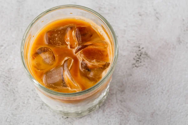 Glass with cold brew coffee and milk isolated on bright marble background. Overhead view, copy space. Advertising for cafe menu. Coffee shop menu. Horizontal photo. — Stock Photo, Image