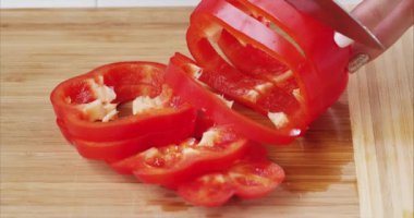 Modern bir mutfağın tahta tahtasında kırmızı dolma biber kesen kadın ellerine yakın çekim. Sağlıklı beslenme. Makro. Salata hazırla. 6K Blackmagic kamerasıyla çekildi..