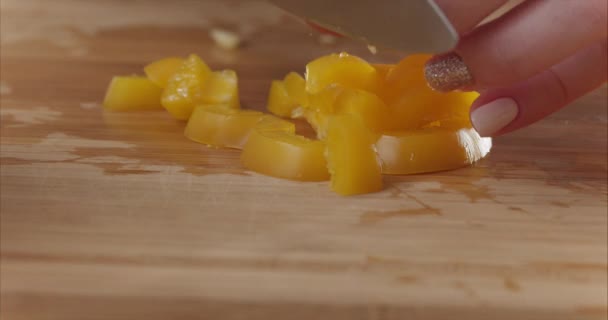 Primer plano de las manos de la mujer cortando pimiento amarillo sobre tabla de madera en una cocina moderna. Dieta saludable. Macro. Prepara una ensalada. Disparo en cámara Blackmagic 6k . — Vídeos de Stock