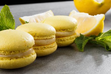 Fransız kurabiyeleri izole edilmiş. Seçici odaklanma. Limonlu ve nane arkaplanlı güzel sarı badem kurabiyeleri. Güzel bir düzenleme. Düz yerde, üst tarafta. Makro fotoğraf.