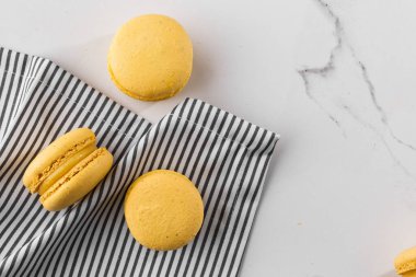 Fransız kurabiyeleri izole edilmiş. Seçici odaklanma. Mermer zemin üzerinde çizgili peçeteli güzel sarı badem kurabiyeleri. Güzel bir düzenleme. Düz yerde, üst tarafta. Makro fotoğraf. Kopyalama alanı ile.