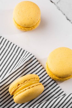 Fransız kurabiyeleri izole edilmiş. Seçici odaklanma. Mermer zemin üzerinde çizgili peçeteli güzel sarı badem kurabiyeleri. Güzel bir düzenleme. Düz yerde, üst tarafta. Makro fotoğraf.