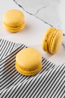 Fransız kurabiyeleri izole edilmiş. Seçici odaklanma. Mermer zemin üzerinde çizgili peçeteli güzel sarı badem kurabiyeleri. Güzel bir düzenleme. Düz yerde, üst tarafta. Makro fotoğraf.