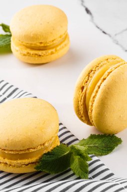 Fransız kurabiyeleri izole edilmiş. Seçici odaklanma. Mermer zemin üzerinde çizgili peçeteli güzel sarı badem kurabiyeleri. Güzel bir düzenleme. Düz yerde, üst tarafta. Makro fotoğraf.