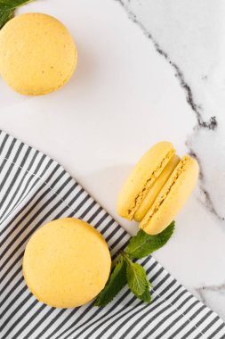 Fransız kurabiyeleri izole edilmiş. Seçici odaklanma. Mermer zemin üzerinde çizgili peçeteli güzel sarı badem kurabiyeleri. Güzel bir düzenleme. Düz yerde, üst tarafta. Makro fotoğraf. Kopyalama alanı ile.