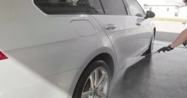 Otomobil yıkama işleminin yavaş çekim videosu, oto yıkama jeti, yüksek basınçlı yıkama ve araba kiri. Yan Görünüm. Arabadan köpüklü deterjan drenajı. 4k