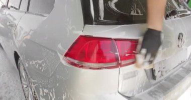Gümüş arabada köpüklü sünger yıkayan erkek eli. Araba servisi kavramı, Oto Yıkama. Parlak arabanın dış kısmına köpük yaymak ağır çekim. Araba yıkama ya da araba yıkama fiyatları. 4k