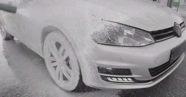 Close-up van een carwash met speciaal wit schuim voor het reinigen van auto 's en auto' s. Contactloze autowasstraat. Autoeigenaar wast zijn vuile auto. Transport desinfectie. 4k — Stockvideo