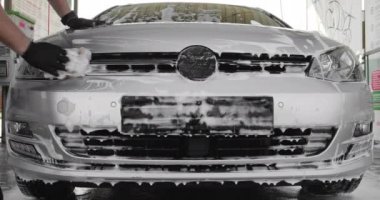 Gümüş arabada köpüklü sünger yıkayan erkek eli. Araba servisi kavramı, Oto Yıkama. Parlak arabanın dış kısmına köpük yaymak ağır çekim. Araba yıkama ya da araba yıkama fiyatları. 4k