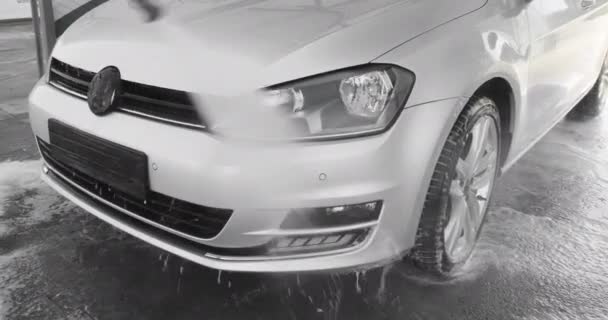 Slow Motion Video of a Car Washing Process on a Self-Service Car Wash. A Jet of Water with a High Pressure Wash Off the Dirt From the Car. Вид сбоку. Пеноотделитель вытекает из машины. 4k — стоковое видео