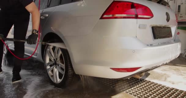 Slow Motion Video of a Car Washing Process on a Self-Service Car Wash. A Jet of Water with a High Pressure Wash Off the Dirt From the Car. Вид сбоку. Пеноотделитель вытекает из машины. 4k — стоковое видео