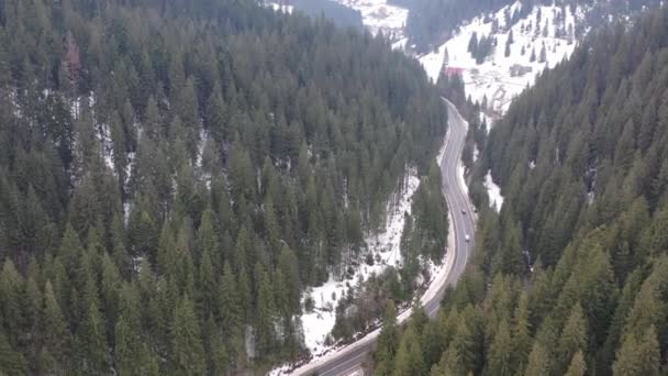Auto auf winterlicher Landstraße im verschneiten Wald, Luftaufnahme von der Drohne in 4k. Luftaufnahme des Waldes mit hohen Kiefernwäldern, bedeckt mit Neuschnee an sonnigen Tagen entlang der langen Straßen. — Stockvideo