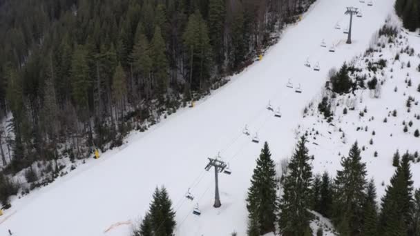 Widok z wyciągu dla narciarzy i snowboardzistów na zaśnieżonym stoku. Wyciąg wyciąga ludzi na szczyt góry. Wyciąg narciarski na śnieżnej górze. Aktywność zimowa. 4k — Wideo stockowe
