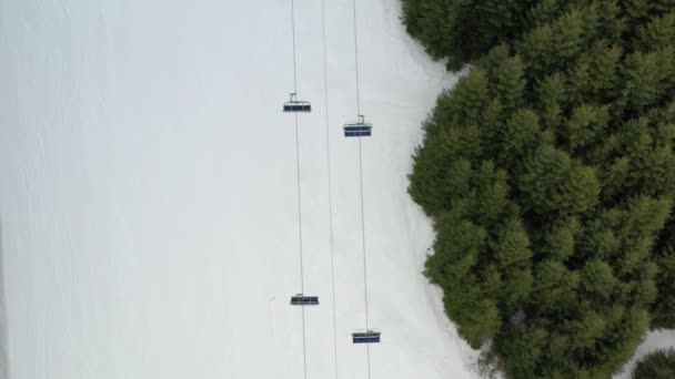 为滑雪者和雪地斜坡上的滑雪者提供无人滑雪机升降的俯视图。滑雪能把人抬到山顶.雪山上的滑雪电梯。冬季活动。4k — 图库视频影像