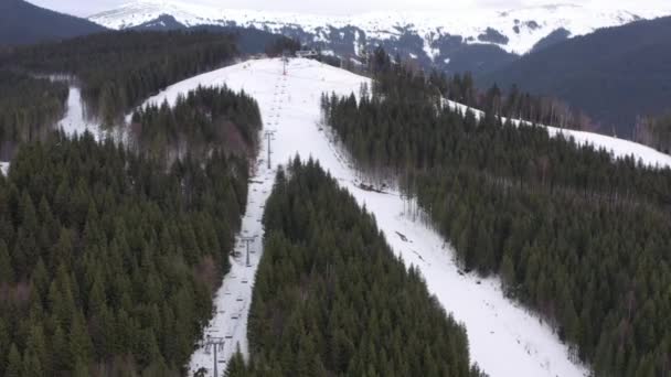 雪の斜面に輸送スキーヤーやスノーボーダーのためのドローンスキーリフトからのトップビュー。スキーリフトは山の頂上に人々を持ち上げます。雪の山のスキーエレベーター。冬のアクティビティ。4k — ストック動画