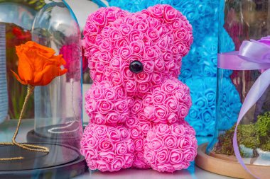 Foamiran ve kağıttan yapılmış yapay çiçekler. Yapay güller. Tahta kapı kulpunu tebrik etmek için plastik çiçek buketinden ve oyuncak ayıdan yapılmış pembe bir oyuncak ayı.