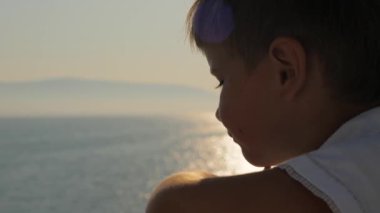 Gemiden denize bakan mutlu çocuk. Gezi sırasında genç bir turist. Gemide beyaz tişörtlü genç bir gezgin var. Yaz tatili. Mutlu bir çocukluk. Turizm geçmişi. Denizde bir tatil. Turizm konsepti. Seyahat acentası reklamı.