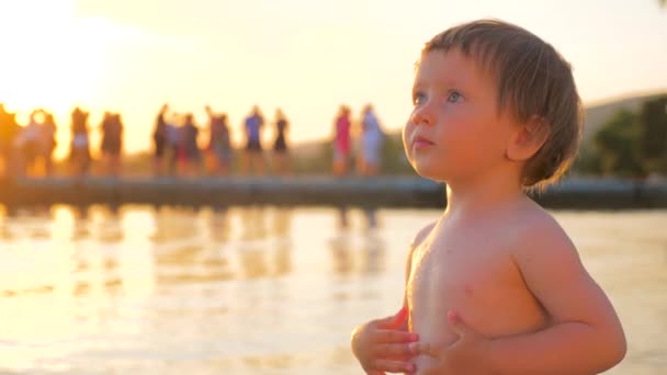 Espressione facciale. Buona infanzia. Bellissimo ragazzo in piedi sulla spiaggia. Uno sguardo speciale. Ragazza età 12-24 mesi con sguardo profondo si erge sul fondo del mare crepuscolo — Video Stock