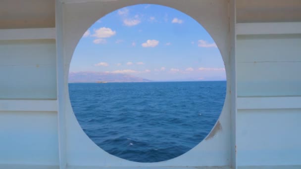 Letní mořská pláň z kulatého okna jachty. Vodní doprava. Cestovní koncept. Pohled na moře z kabiny výletní lodi. Pohled na západ slunce a oceán okénkem lodi — Stock video