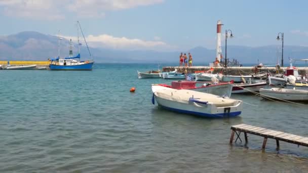 Концепция путешествия. Рыбацкие лодки на морской воде и пирс с молодежью на нем. Туризм. Вид на Грецию, море с рыбацкими лодками и пирсом на нем. Туристы на пирсе с рыбой — стоковое видео