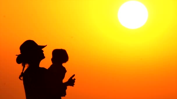 Mère gracieuse avec enfant. Bébé sur les mains des mères sur fond de coucher de soleil. Silhouettes de parent avec enfant sur fond de coucher de soleil. Bonne famille. Une famille d'enfants. Famille monoparentale . — Video