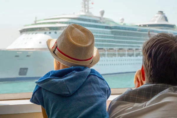 Family travel concept. Cruise with family. Sea transport. Adult and kid looking through window on liner, ship. Father and son at the port sitting in ship. Family recreations. Reflections on traveling.