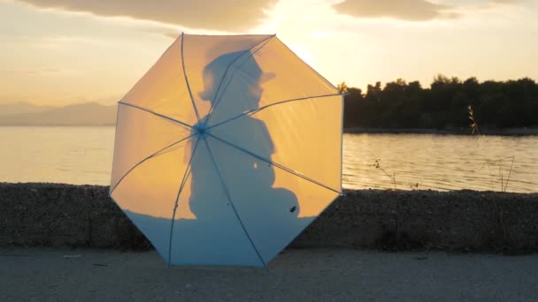 Glad pojke 5-6 längtar gamla promenader längs kusten med paraply i händerna. Porträtt av Happy Boy Holding paraply i handen. Happy Childhood koncept. Lycklig liten pojke med solnedgång på bakgrunden — Stockvideo