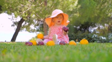 Küçük Prenses meyve açık oynuyor. Panama çocuk arka bahçede eğlenceli açık sahip. Mutlu çocukluk konsepti. Toddler yeşil çim üzerinde anne bekliyor oturan.