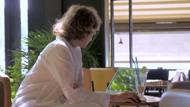 Ung urban digital kvinna i tusenårig generation z ålder sitter på resort eller resmål semester, fungerar på laptop, uppdateringar ansökan eller kontrollerar e-postmeddelanden, fjärrkontor jobb — Stockvideo
