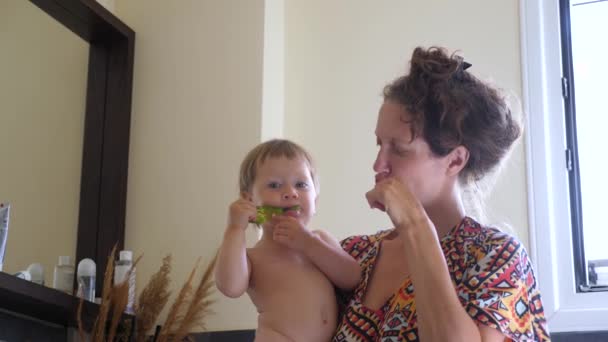 Zorg voor tanden achtergrond. Moederschap achtergrond. Moeder en kind poetsen de tanden in de badkamer. Gelukkig familieconcept. Eerste tanden. Familie gezondheidszorg, geneeskunde. Achtergrond van de kindergeneeskunde — Stockvideo