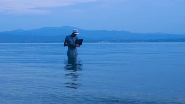 Joven hombre de negocios trabajando en el ordenador portátil en la naturaleza. Trabajo independiente en línea. Concepto de vacaciones, estilo de vida y trabajo . — Vídeos de Stock