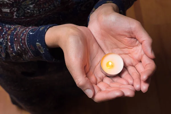 Praying with candle. Candle in hands. Females hands with can Woman against abortion. Tea candle in hands of woman. Mercy background. Sorrow for deliberate termination of a human pregnancy. — Stock Photo, Image