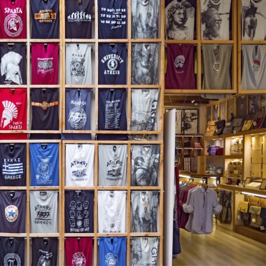 Tişörtleri ve diğer kıyafetleri olan Yunan hediyelik eşya dükkanı. Avrupa 'ya, Yunanistan' a git. Ulusal hatıra geçmişi. Geleneksel hediyelik eşya dükkanı. Yunanistan 'da alışveriş geçmişi. Turizm sektörü