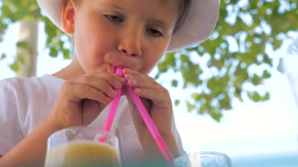 Little tourist drinking fresh juice outdoor. Refreshing drink with ice. Summer Cold drinks for hot summer. Young tourist drinks from two straws. Hipster in hat drinking fresh juice. Traveling concept — Αρχείο Βίντεο