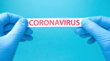 Coronavirus geçmişi. Tıbbi eldivenlerdeki eller üzerinde koronavirüs olan bir kağıt parçası tutuyor. Covid-19 - Wuhan Roman Coronavirus pnömonisi: Tehlikeli virüs, bakteri.