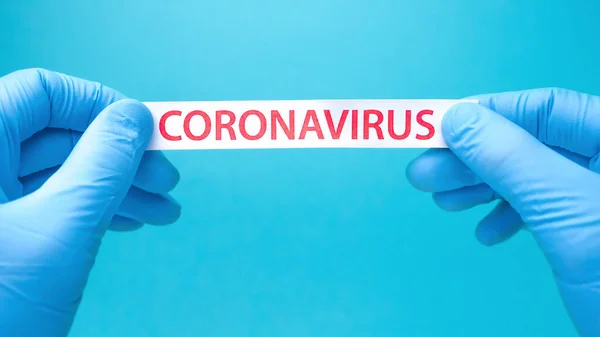 Antecedentes de coronavírus. As mãos em luvas médicas seguram um pedaço de papel com coronavírus impresso nele. Covid-19 - Wuhan Novel Coronavirus pneumonia: COVID-19. Vírus perigoso, bactérias . — Fotografia de Stock